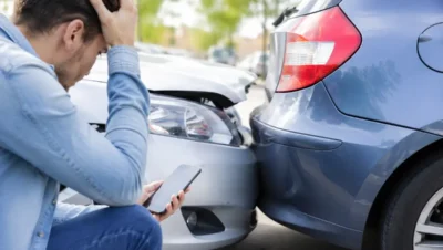 Prejuízo de uma pequena colisão após danos entre dois carros em um estacionamento com motorista preocupado avaliando os custos.