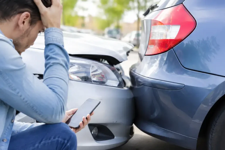 Prejuízo de uma pequena colisão após danos entre dois carros em um estacionamento com motorista preocupado avaliando os custos.